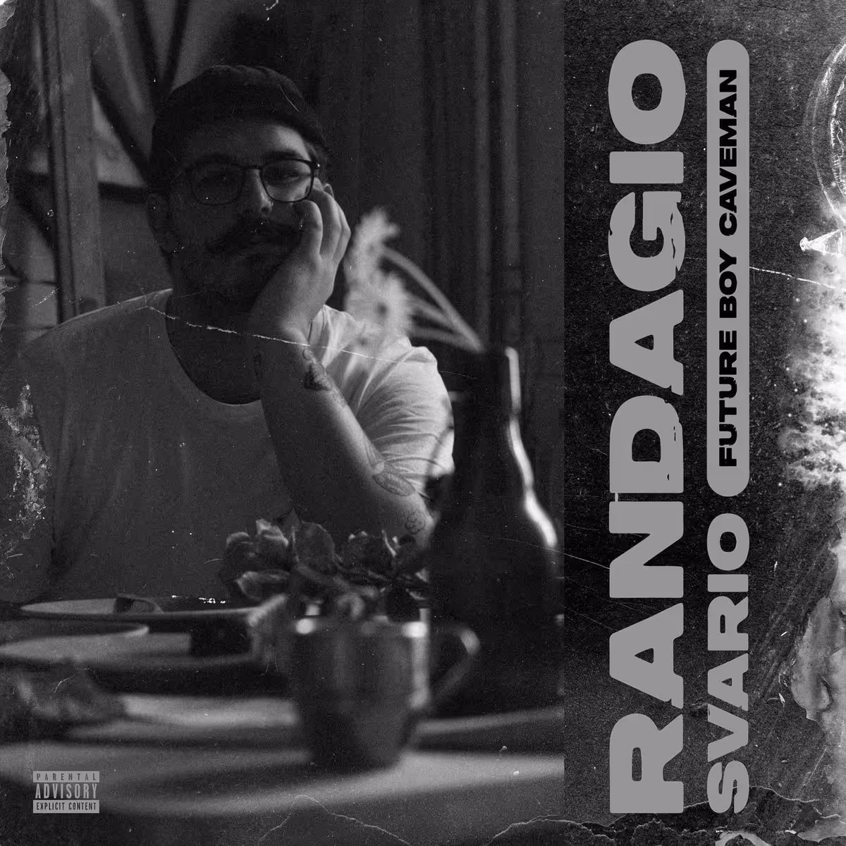 Black-and-white photo of a man with glasses and a mustache resting his head on his hand at a table with food and a bottle, with the text 'Randagio Svario Future Boy Caveman' on the right side.