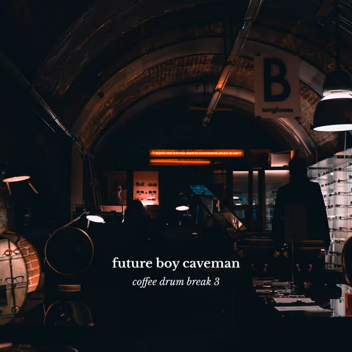Dimly lit shop interior with an illuminated sign reading 'future boy caveman coffee drum break 3' in the center.